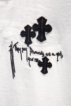 White short-sleeve T-shirt detail: black cross symbols with drips and text graphic.