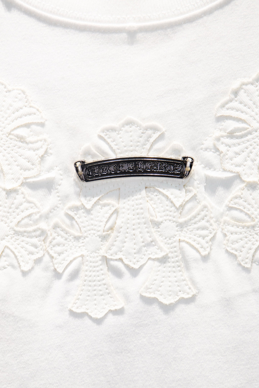 Beaded horizontal bar detail with dark metal on white embroidered fabric