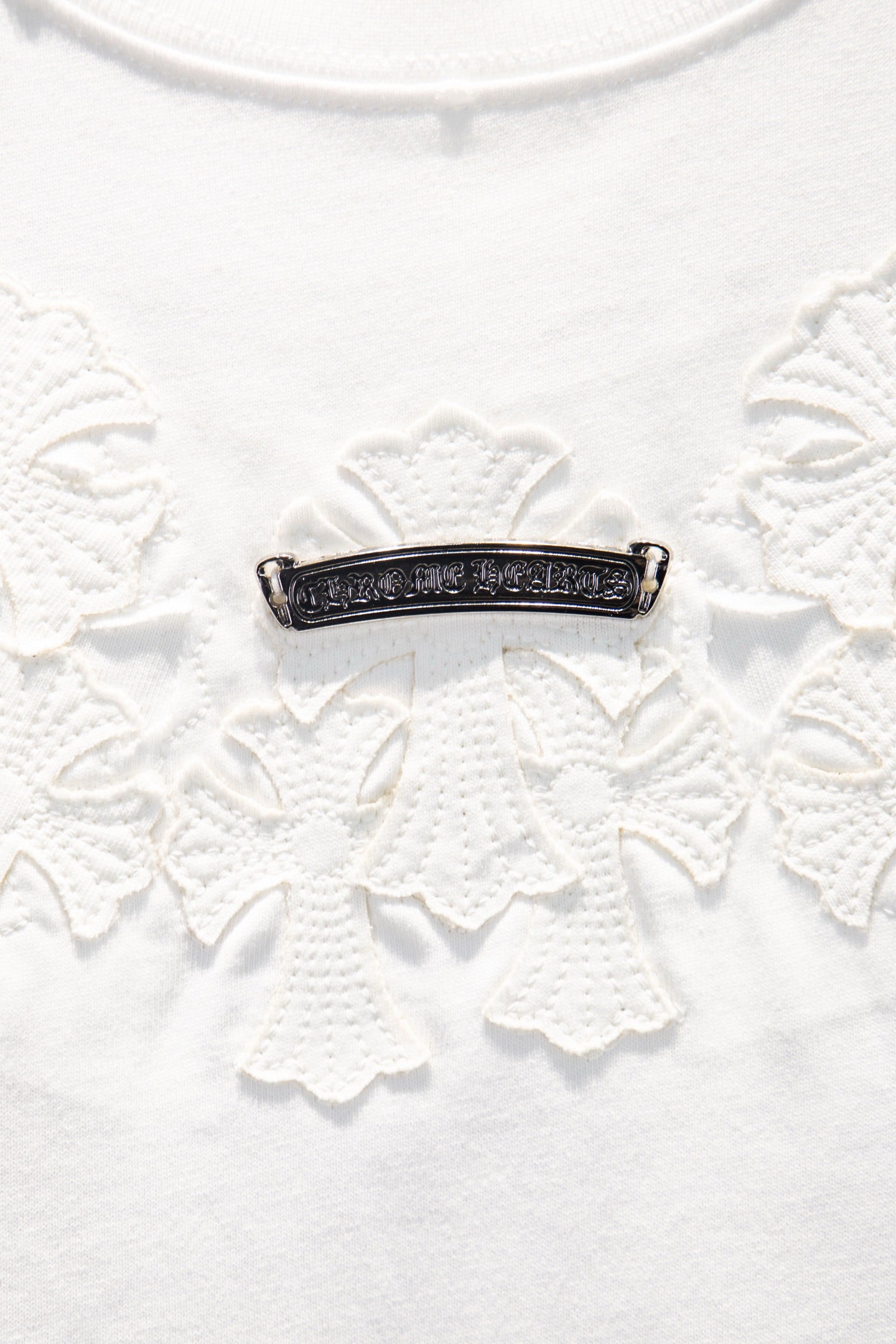 Beaded horizontal bar detail with dark metal on white embroidered fabric