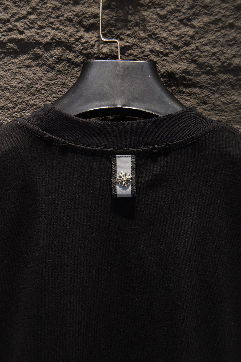 Black T-shirt collar with center neck tag hanging from the neckline