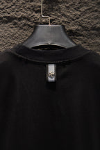 Black T-shirt collar with center neck tag hanging from the neckline