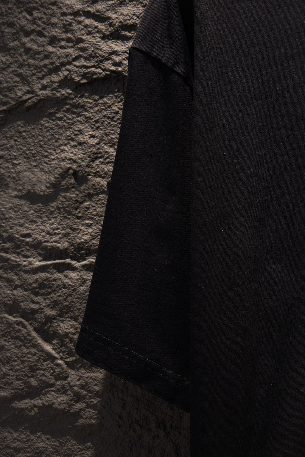 Black short-sleeve T-shirt angled side view showing shoulder and sleeve