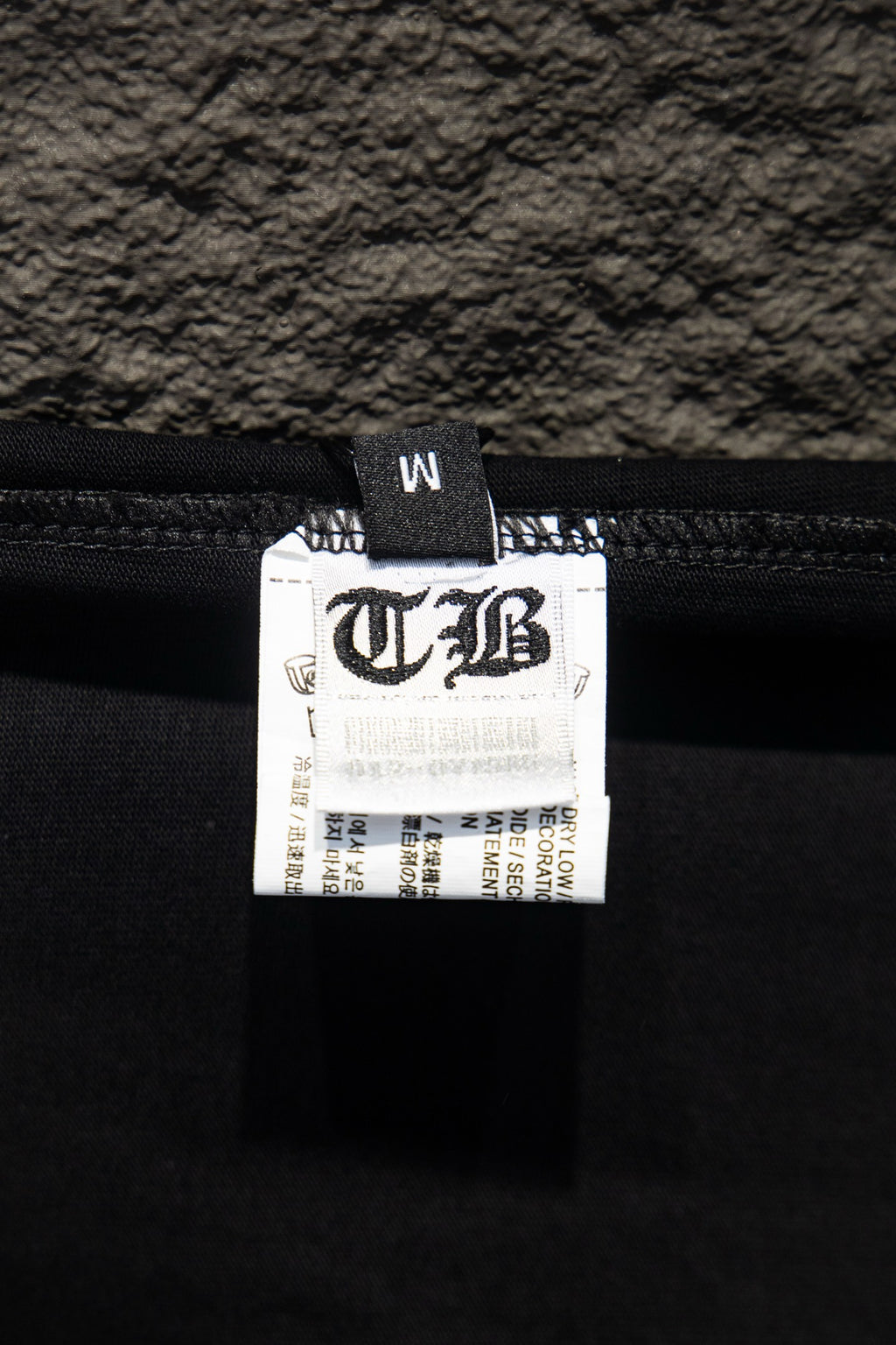 Black T-shirt inner label with printed size and brand information