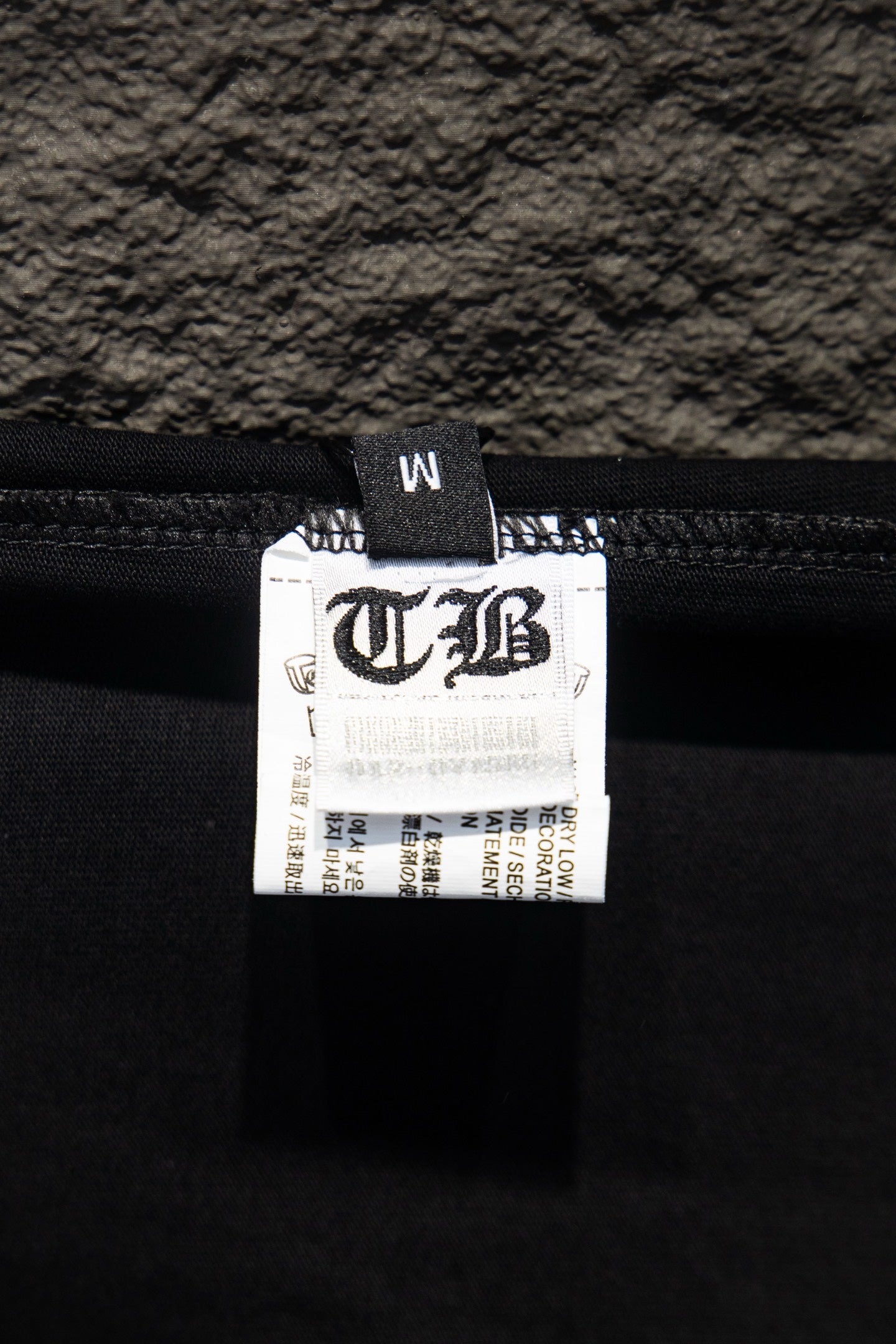 Black T-shirt inner label with printed size and brand information