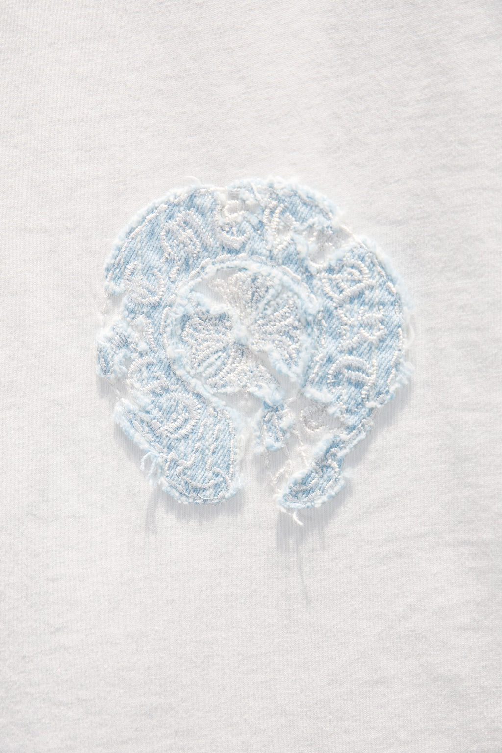 Light blue embroidered face patch on white T-shirt