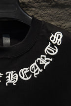 Black T-shirt with white logo graphic text on sleeve, on hanger