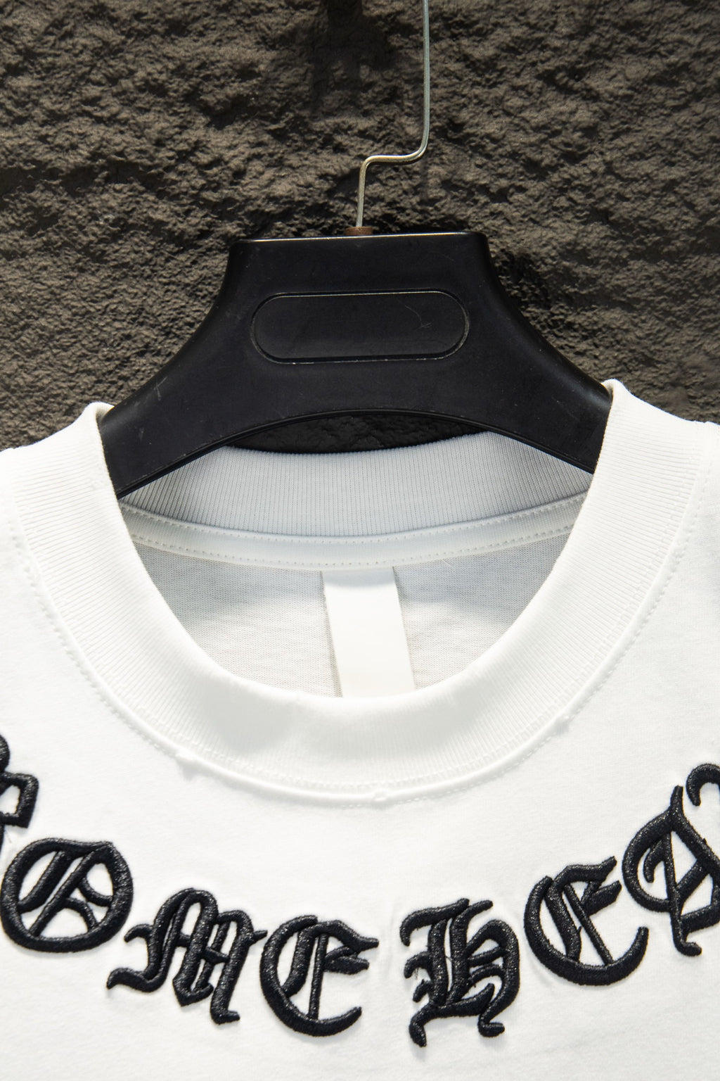 White T-shirt crew neck with black logo embroidery near shoulders
