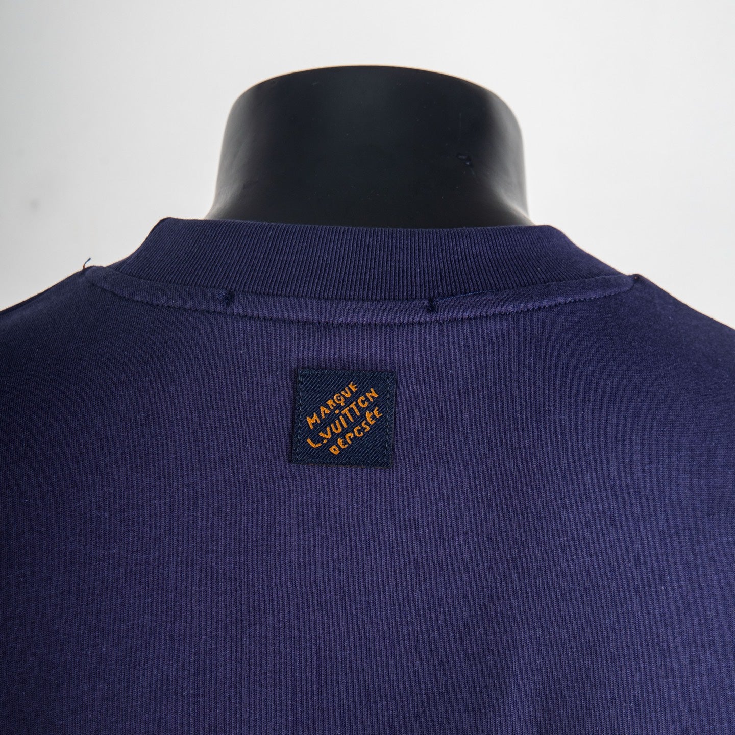 Navy short-sleeve top with small rectangular neck label patch