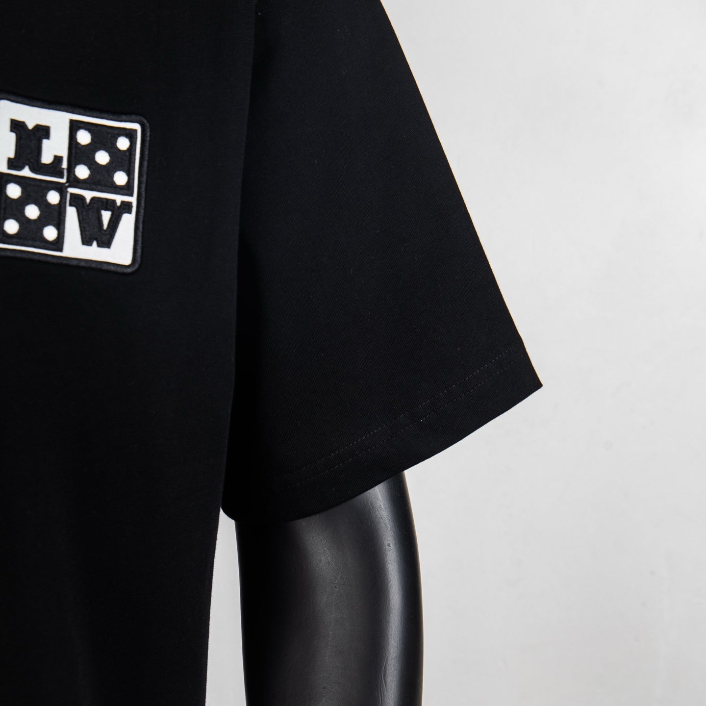 Louis Vuitton black T-shirt sleeve with small square logo patch near shoulder