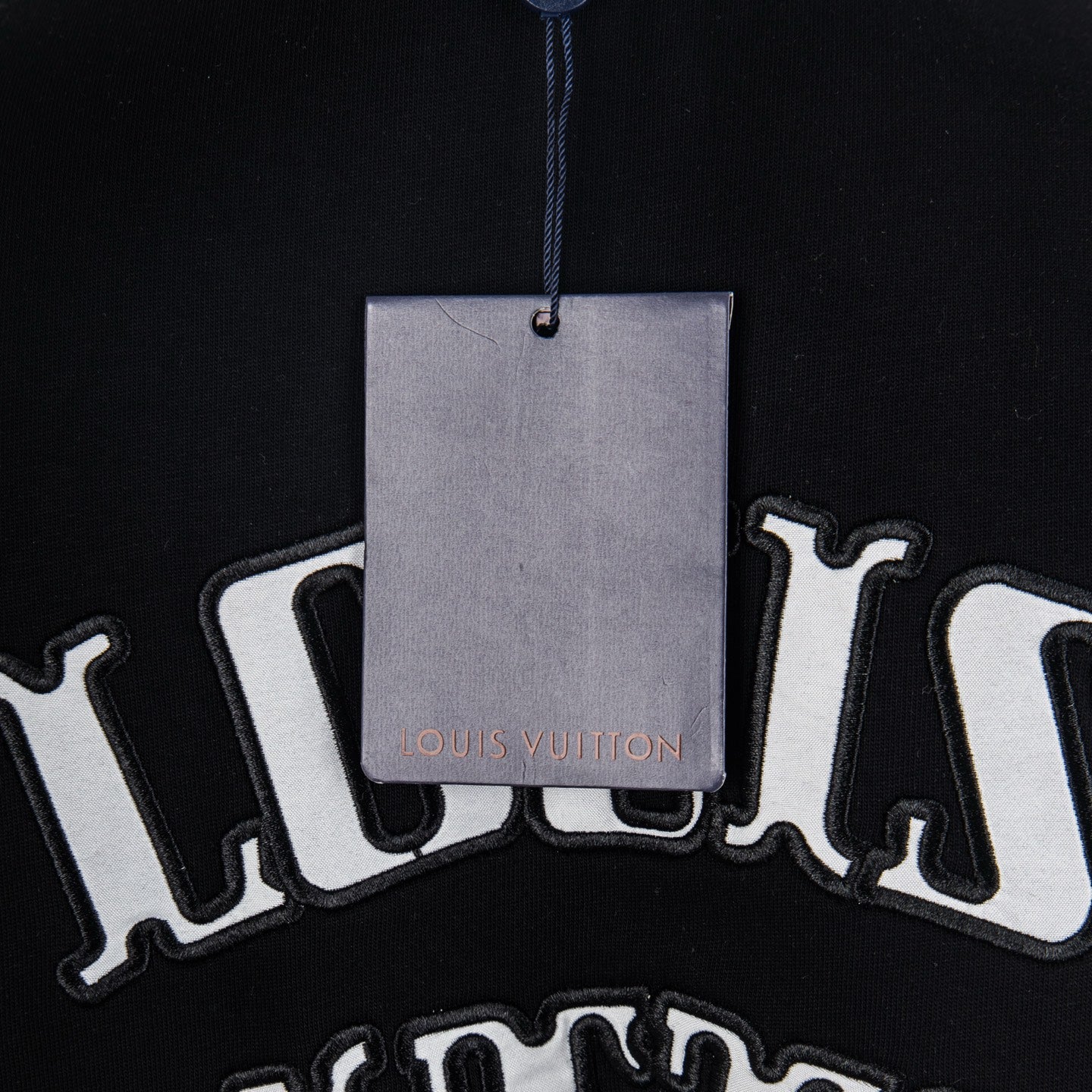 Black T-shirt with hanging tag and Louis Vuitton text graphic