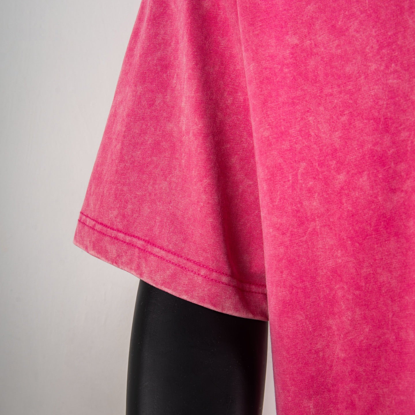 Pink T-shirt with visible side seam and short stitched hem