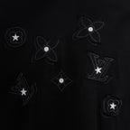 Black T-shirt with dark-on-black flower, star, and LV-style emblems