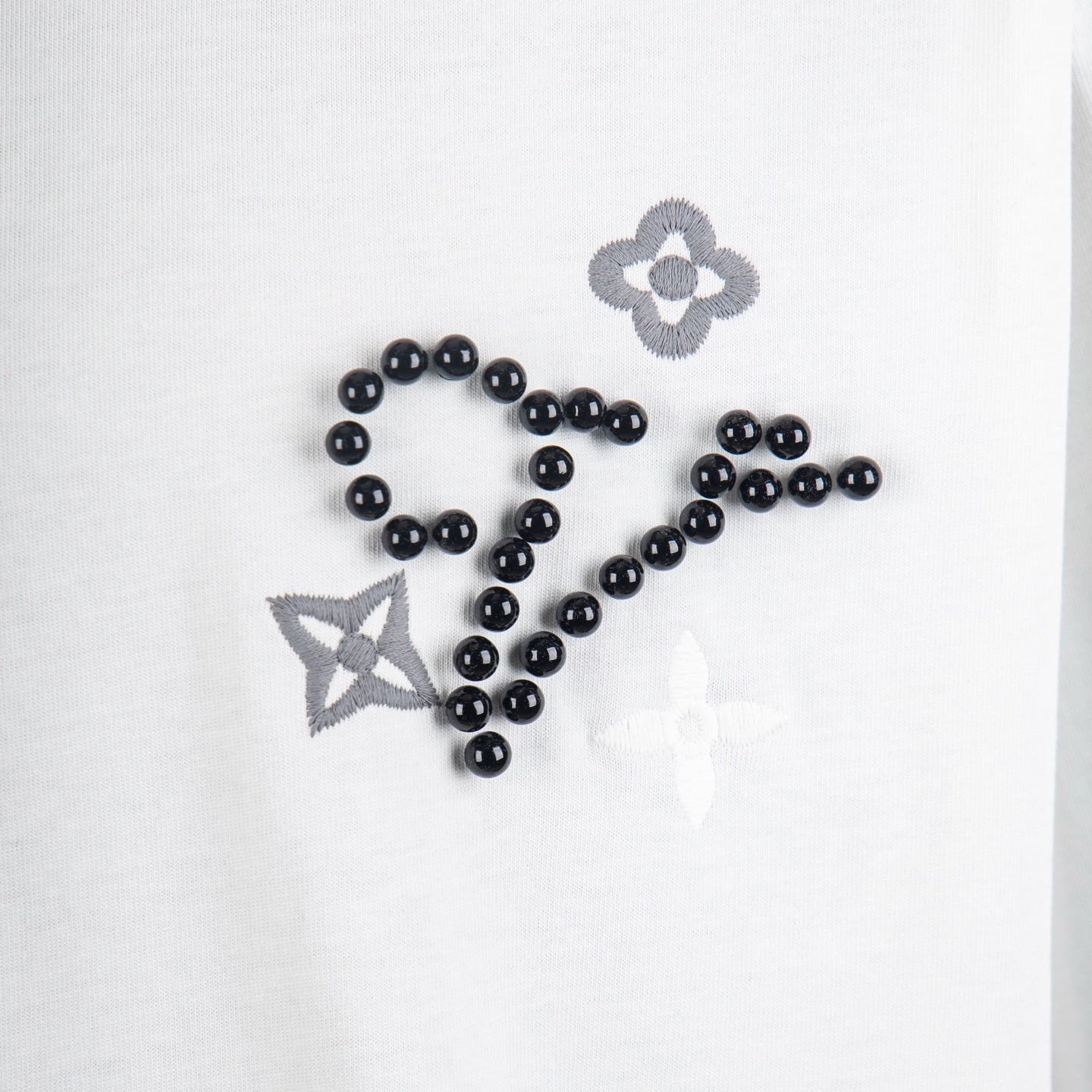 Louis Vuitton white T-shirt detail of black beaded script with flower and star accents