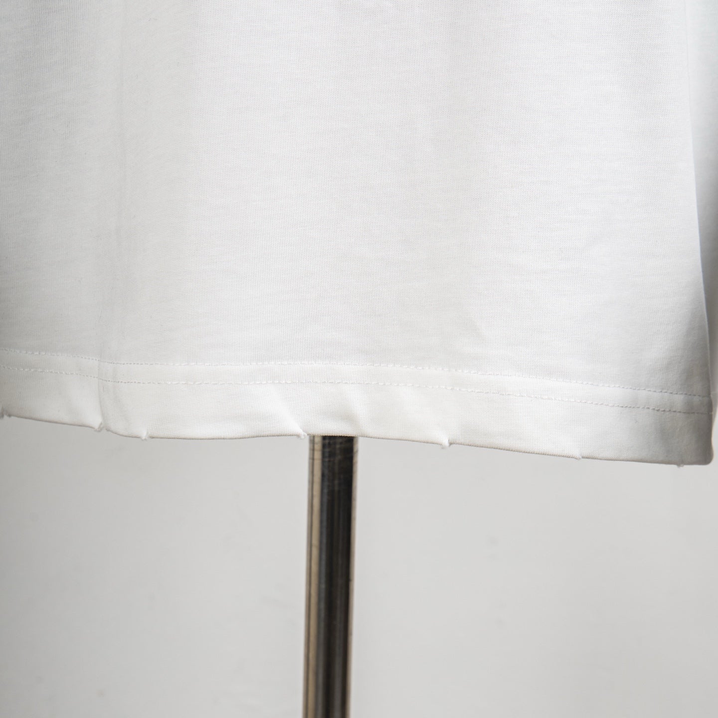 Louis Vuitton white T-shirt hem with visible stitching and drop hemline