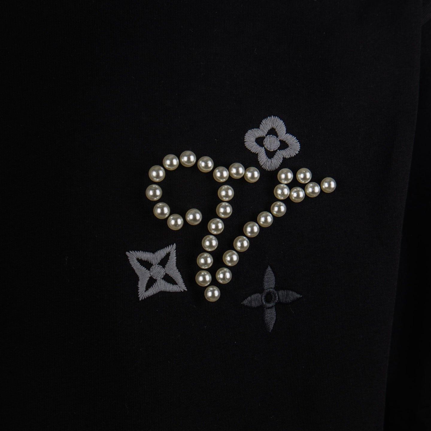 Black crewneck T-shirt front graphic with pearl cursive, stars and flower details