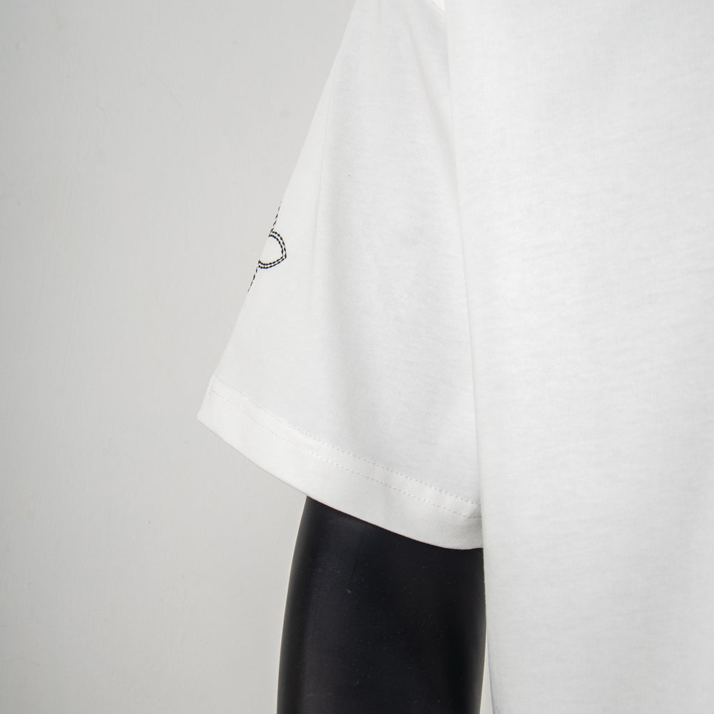 White T-shirt sleeve with small circular motif near the hem