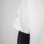 White T-shirt sleeve with small circular motif near the hem
