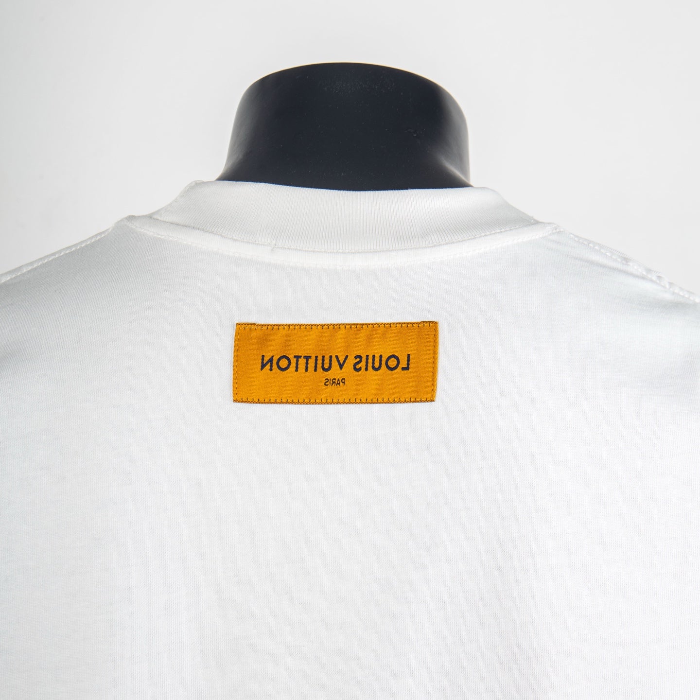 White T-shirt back with rectangular orange brand label at the collar