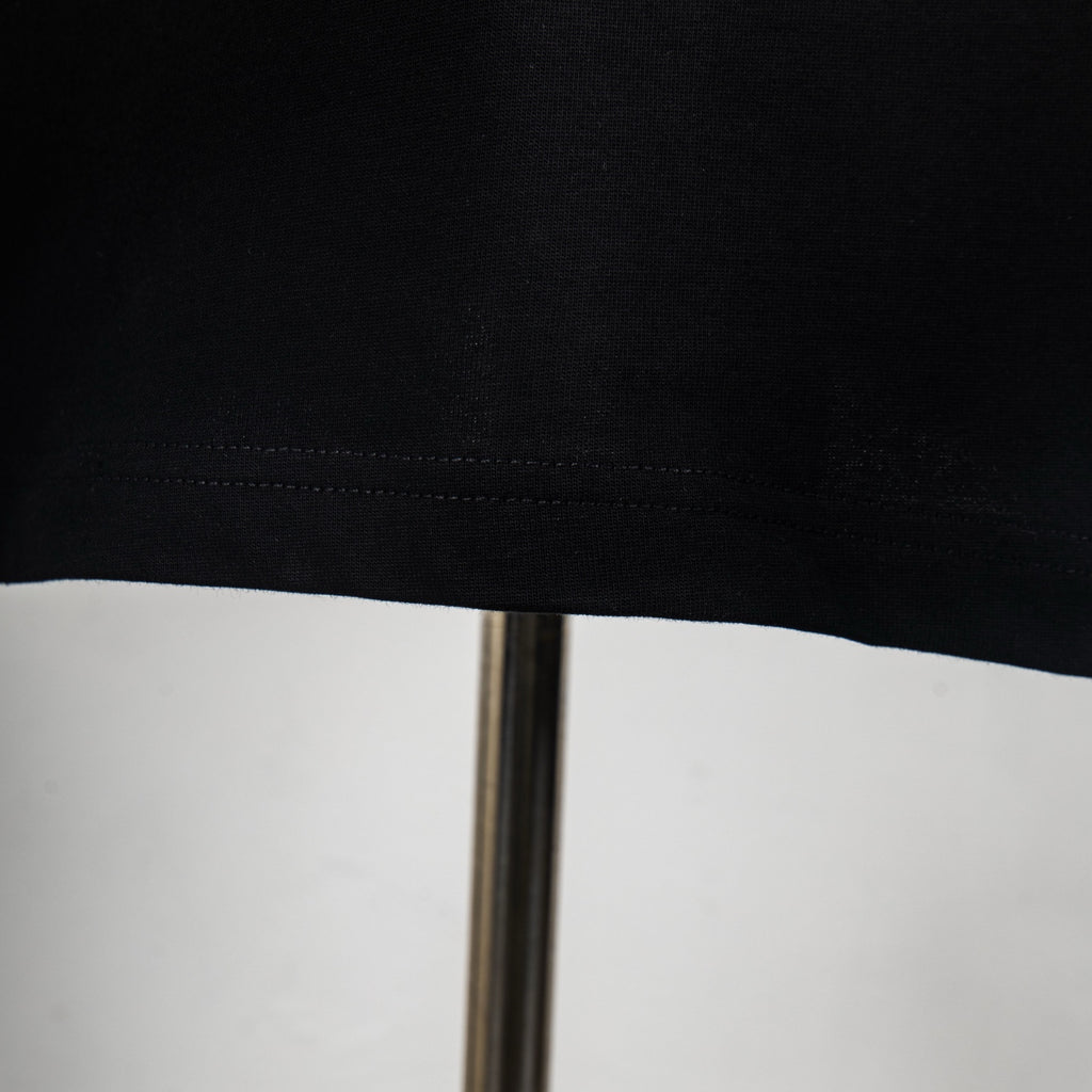 Black T-shirt hem with visible stitching and slight fabric texture