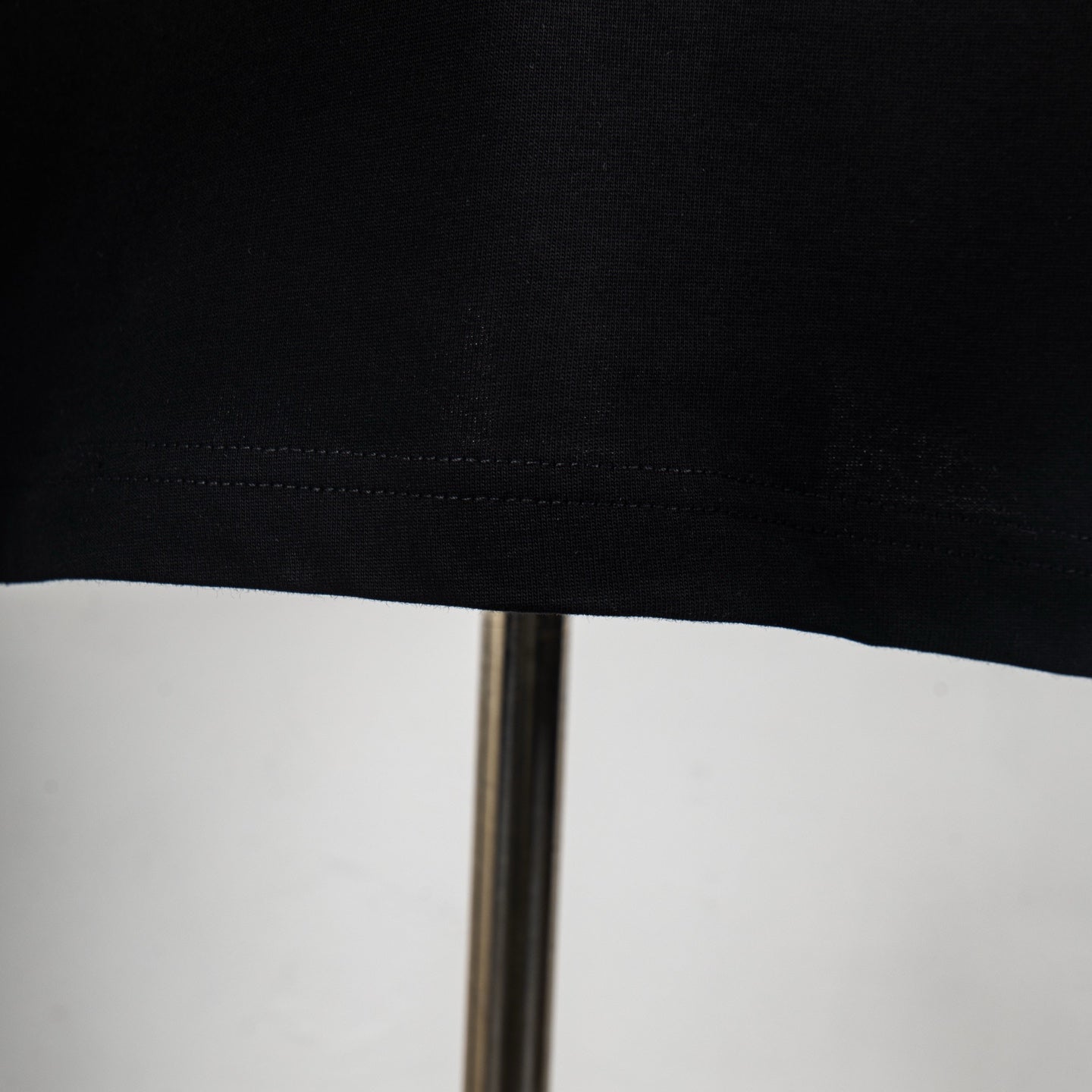 Black T-shirt hem with visible stitching and slight fabric texture