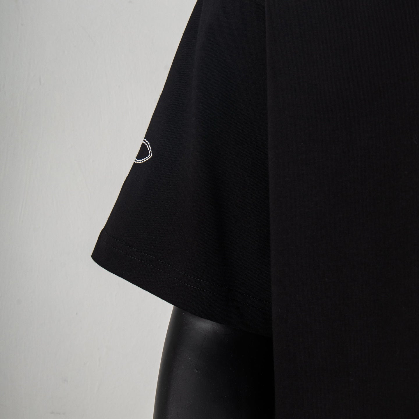 Black short-sleeve T-shirt showing left sleeve hem and side seam