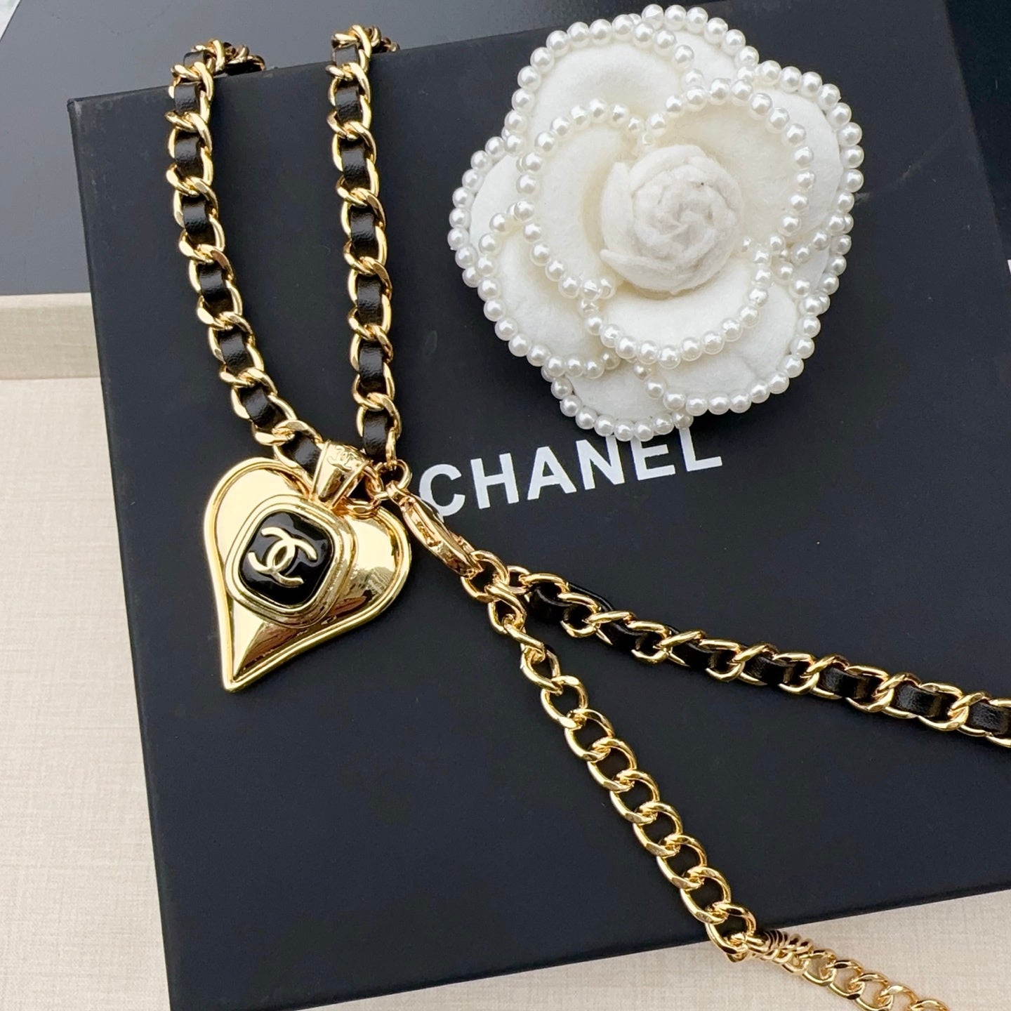 Chanel belt with gold-tone chain links, heart charm, and white camellia detail