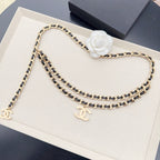 Chanel belt with gold-and-black chain links and white pearl flower embellishment