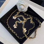 Chanel belt with gold-tone chain and black links, butterfly charms and white floral centerpiece