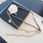 Chanel belt with gold-tone chain, black links, white floral charm and butterfly pendants