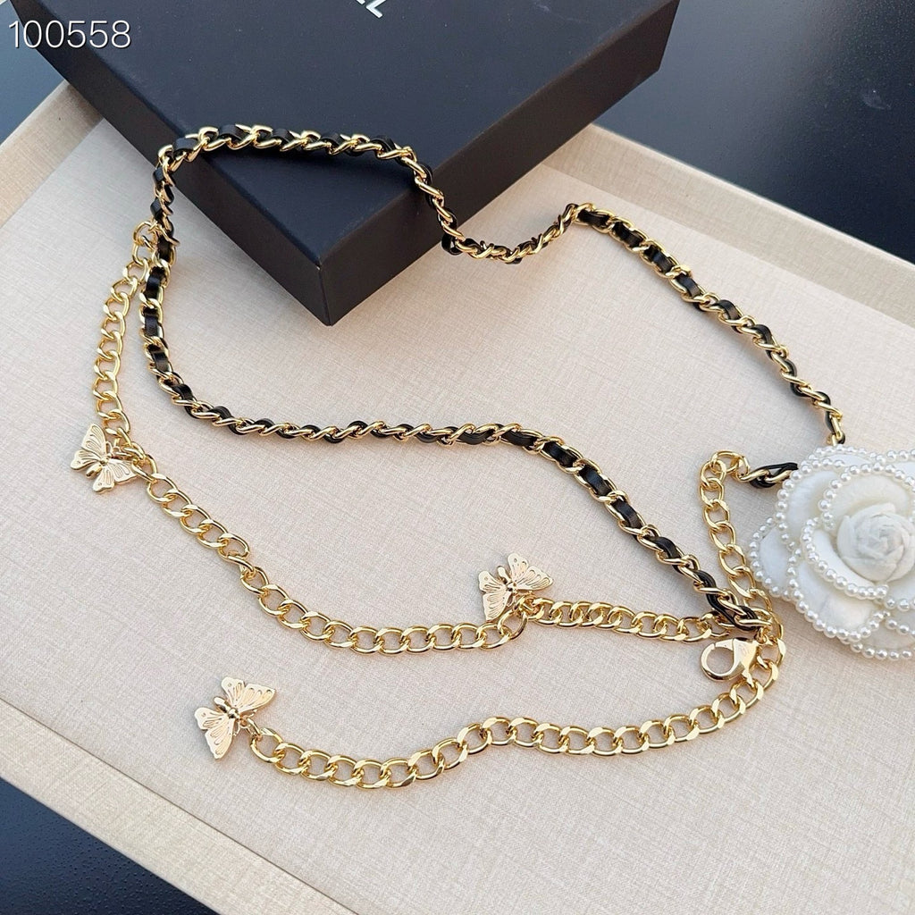Chanel belt with layered gold-tone chains, black links, butterfly charms, and a white floral clip