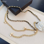 Chanel belt with layered gold-tone chains, black links, butterfly charms, and a white floral clip