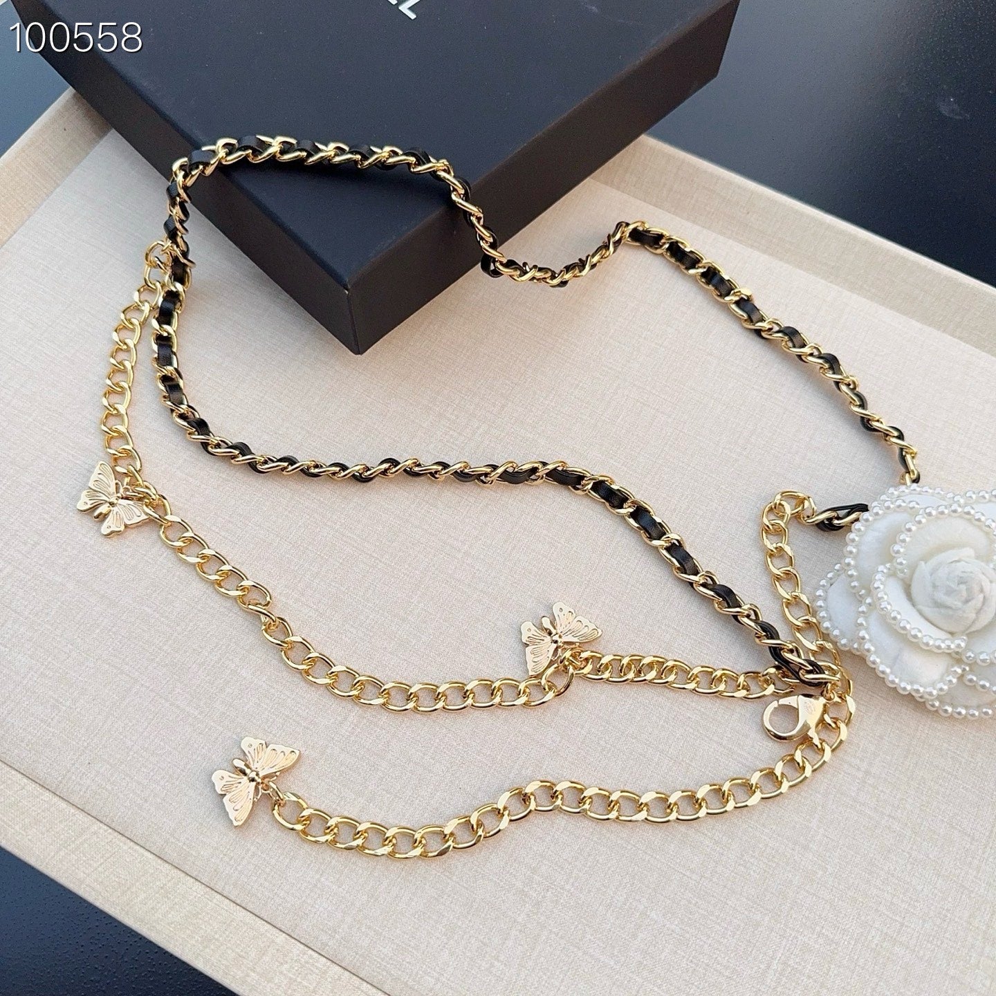 Chanel belt with layered gold-tone chains, black links, butterfly charms, and a white floral clip