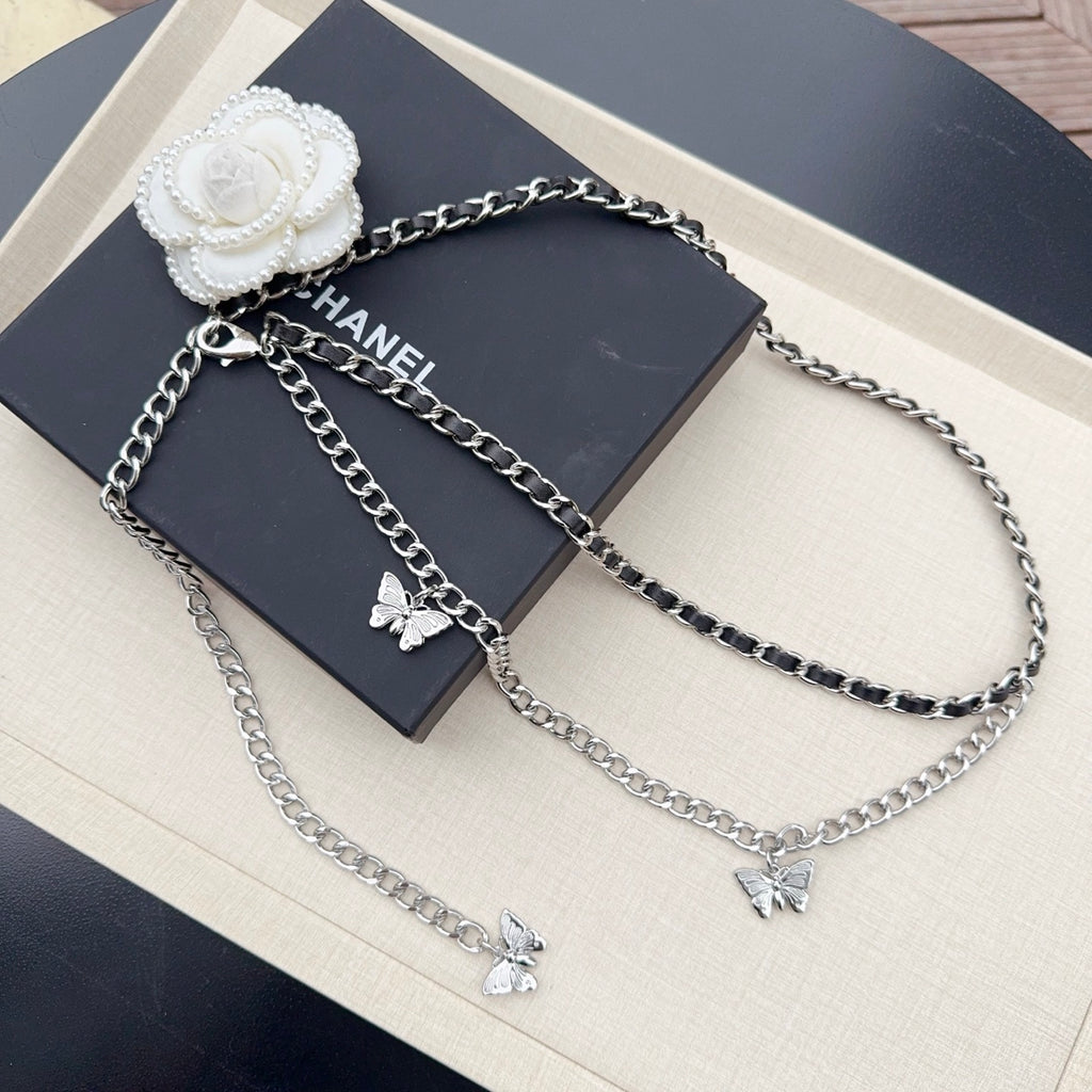 Multi-strand chain belt with silver and dark links, butterfly charms, and a white flower clasp.