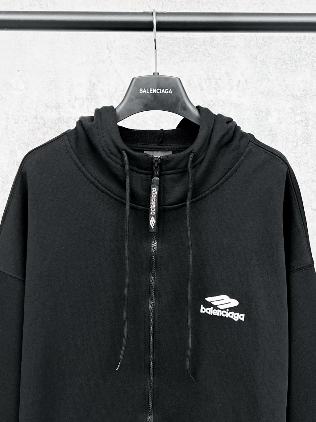 Balenciaga black zip-up hoodie with drawstring hood, central zipper, and chest logo