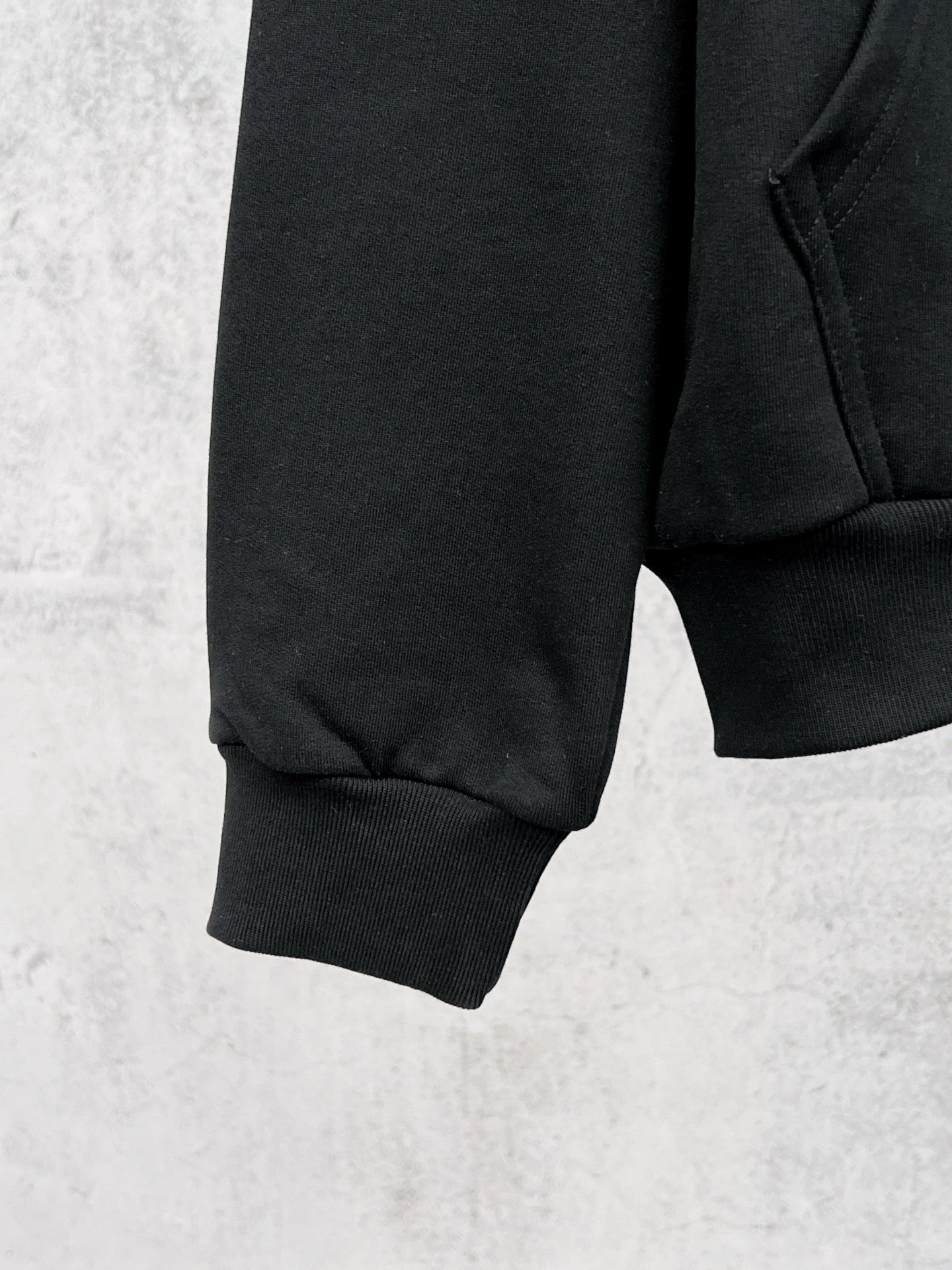 Balenciaga black hoodie quarter view with ribbed cuffs and stitched side seam