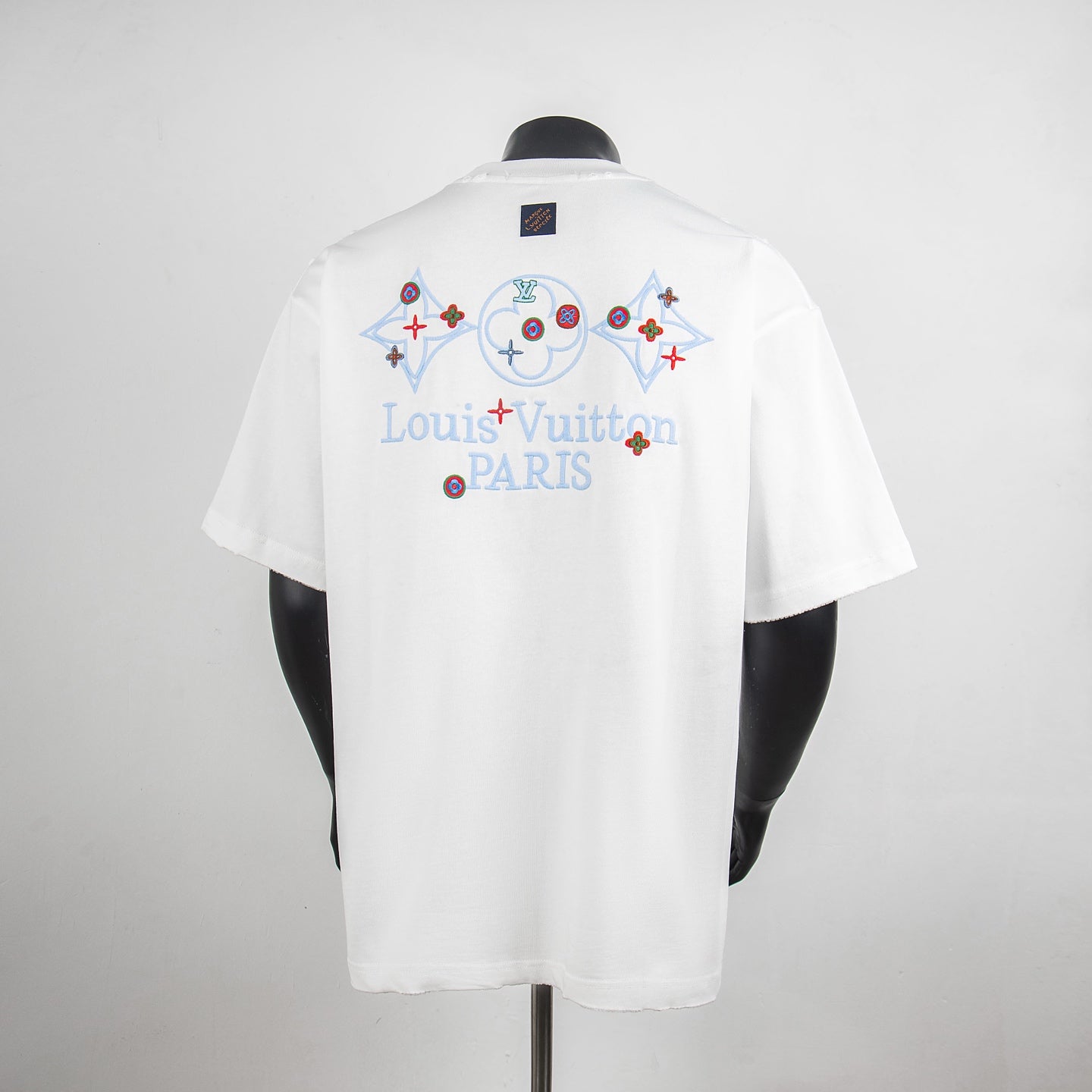 White short-sleeve T-shirt with multicolor back print and blue neck tag