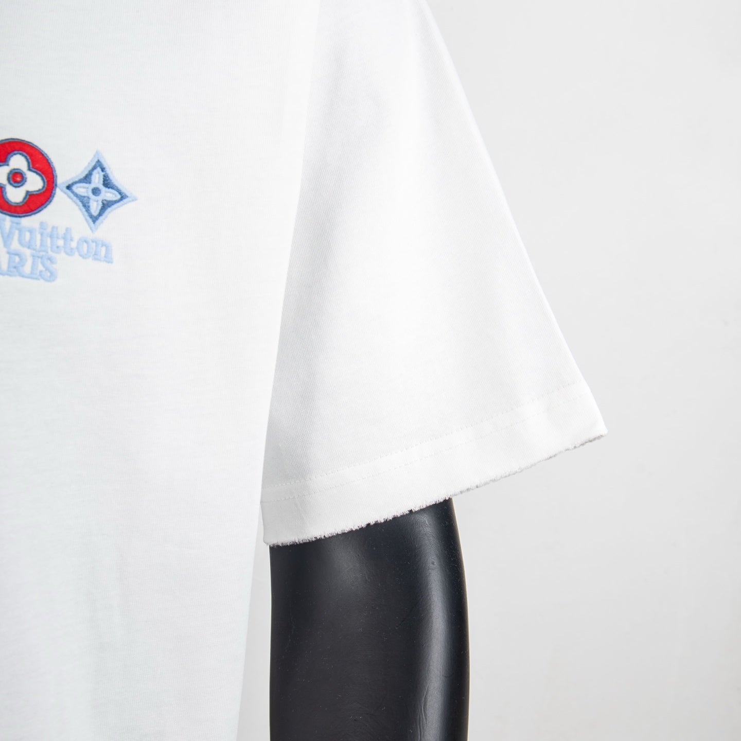 White T-shirt lower side hem on mannequin with embroidered graphic partly visible