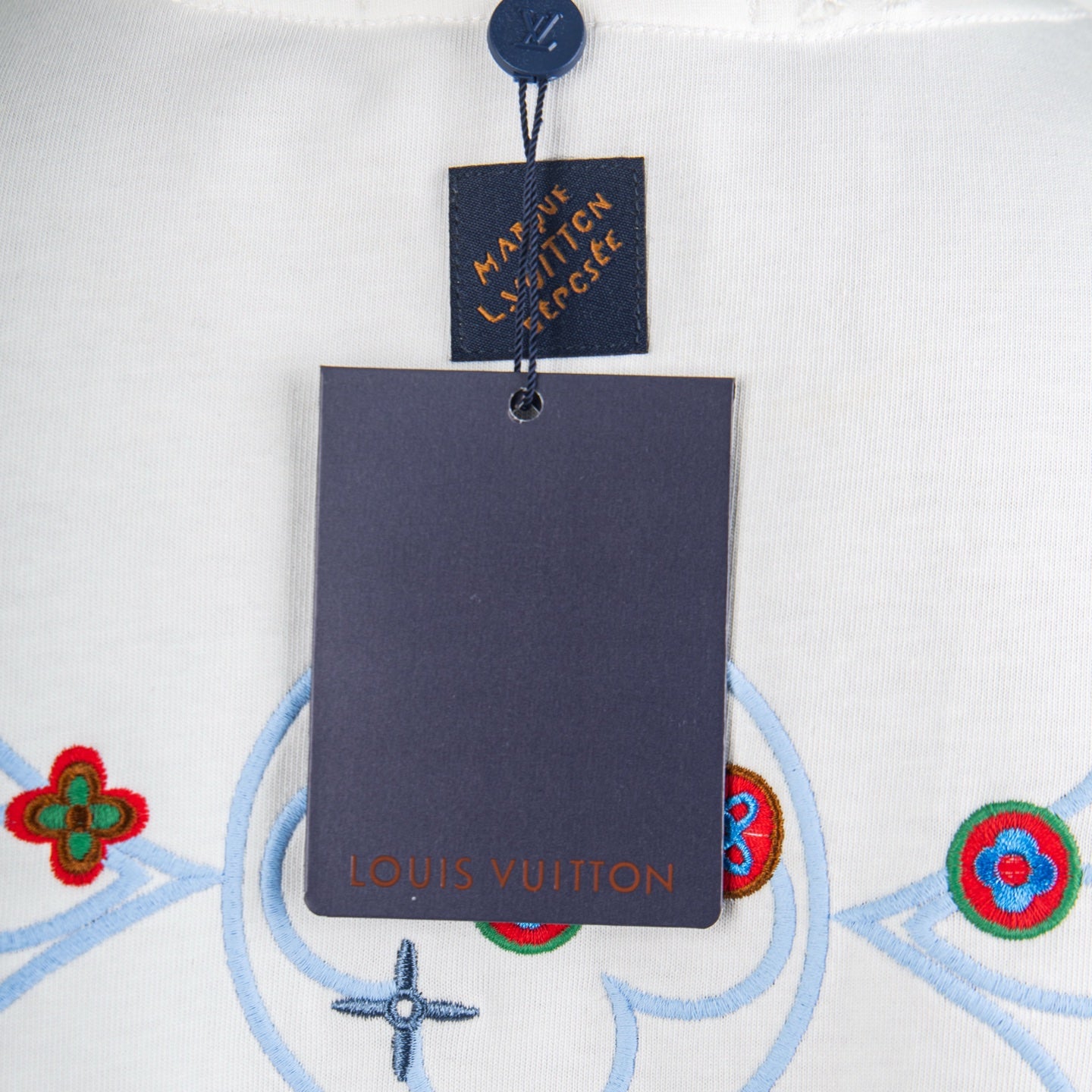 White T-shirt with navy hang tag at collar and embroidered logo details