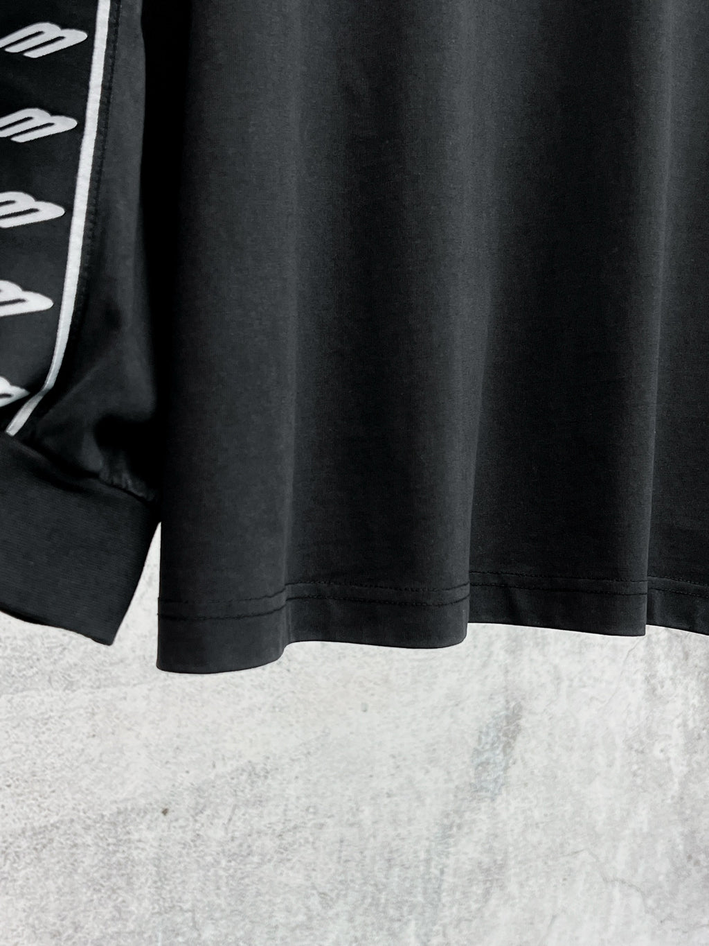 Black long-sleeve shirt hem with white Balenciaga logo stripe sleeve detail