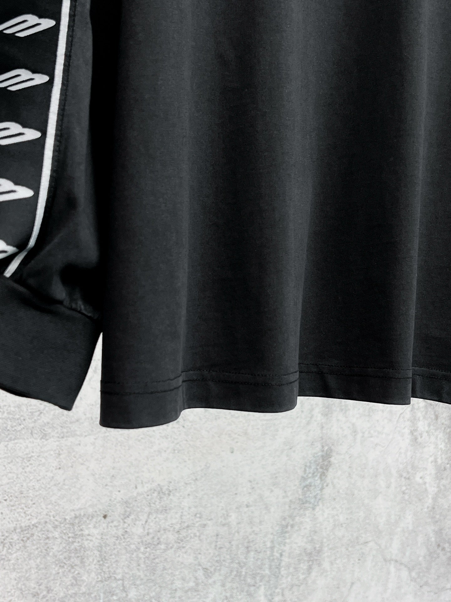 Black long-sleeve shirt hem with white Balenciaga logo stripe sleeve detail