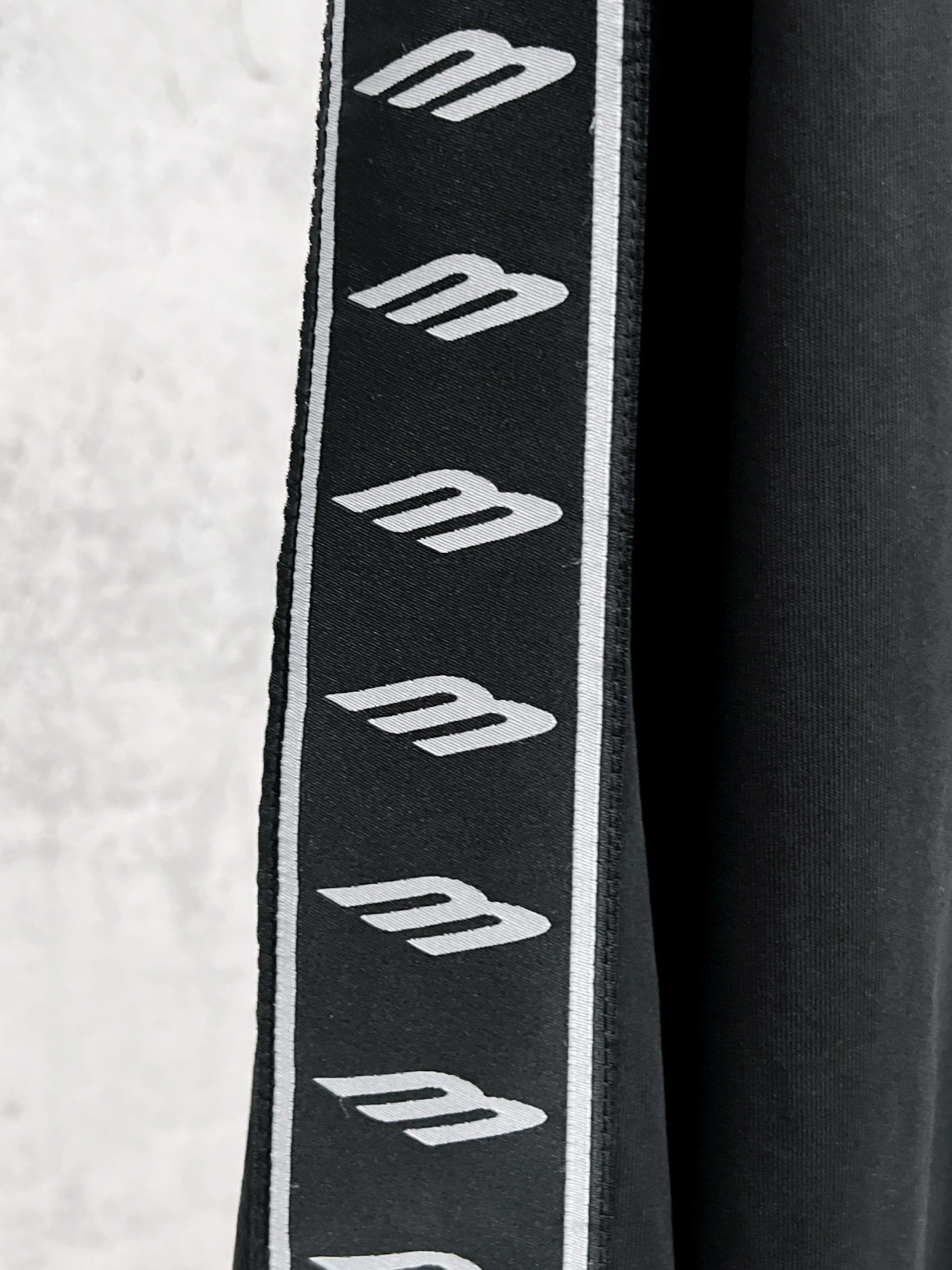 Black sleeve panel with repeating white Balenciaga logo stripes