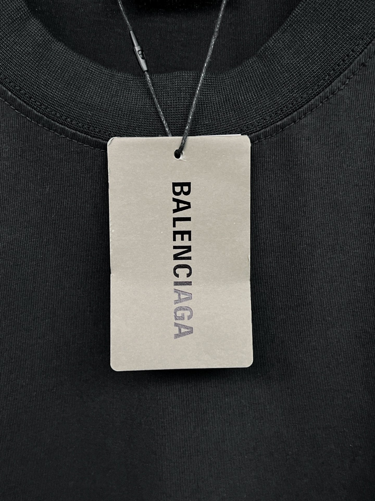 Black long-sleeve shirt neck label on a hanging tag marked Balenciaga