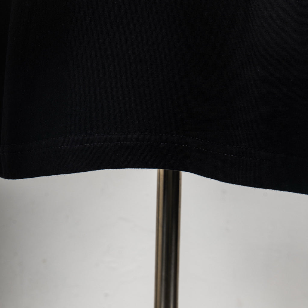 Black T-shirt hem with visible stitching on the lower edge.