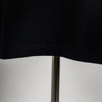 Black T-shirt hem with visible stitching on the lower edge.