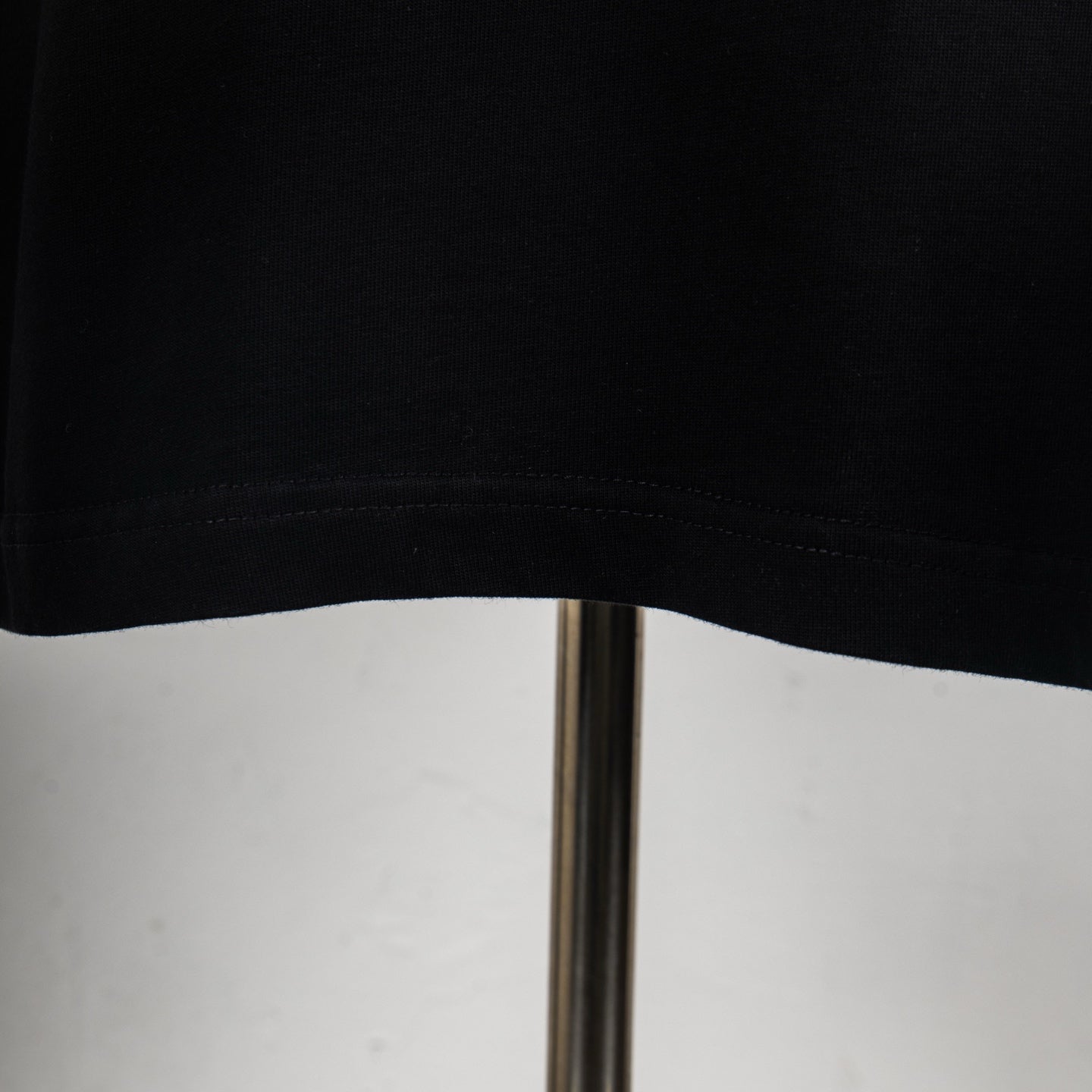 Black T-shirt hem with visible stitching on the lower edge.