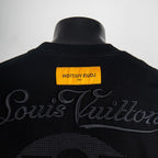Black T-shirt back neckline with Louis Vuitton script and yellow label.