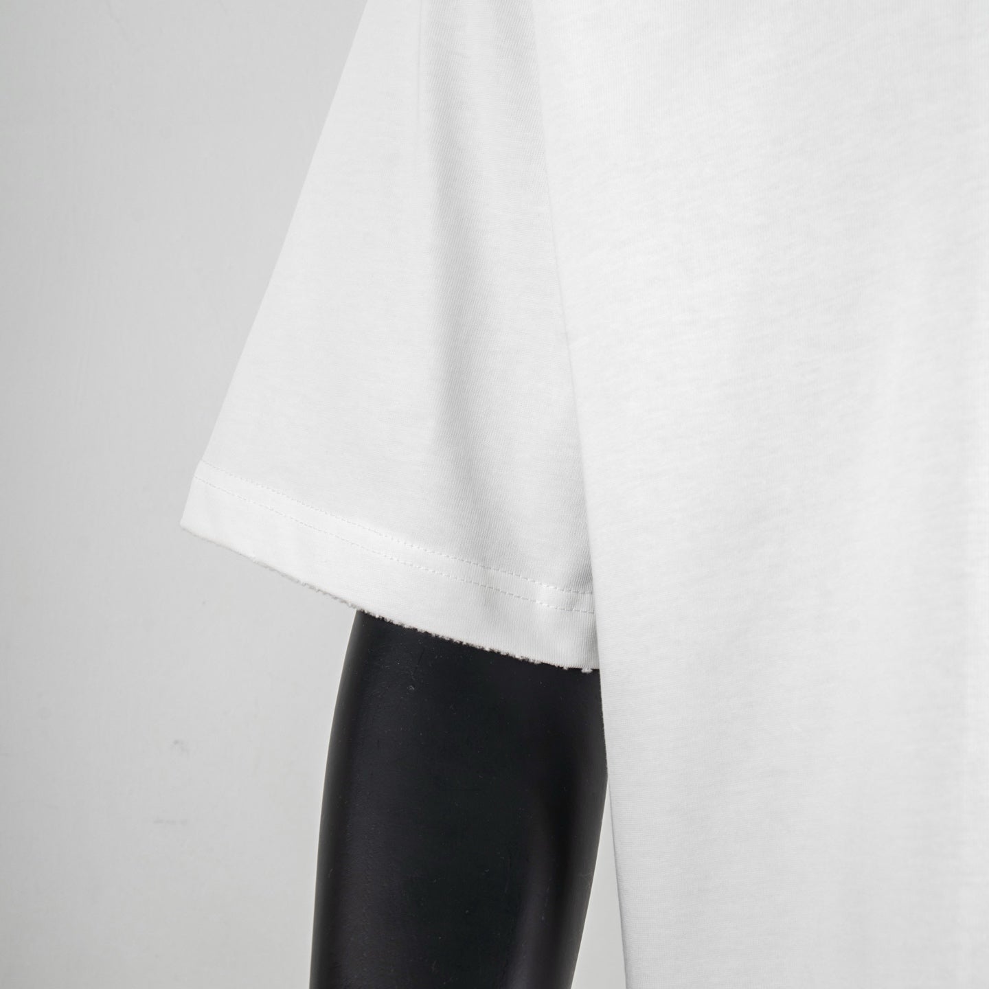 White T-shirt side view showing loose short-sleeve cut and curved hem