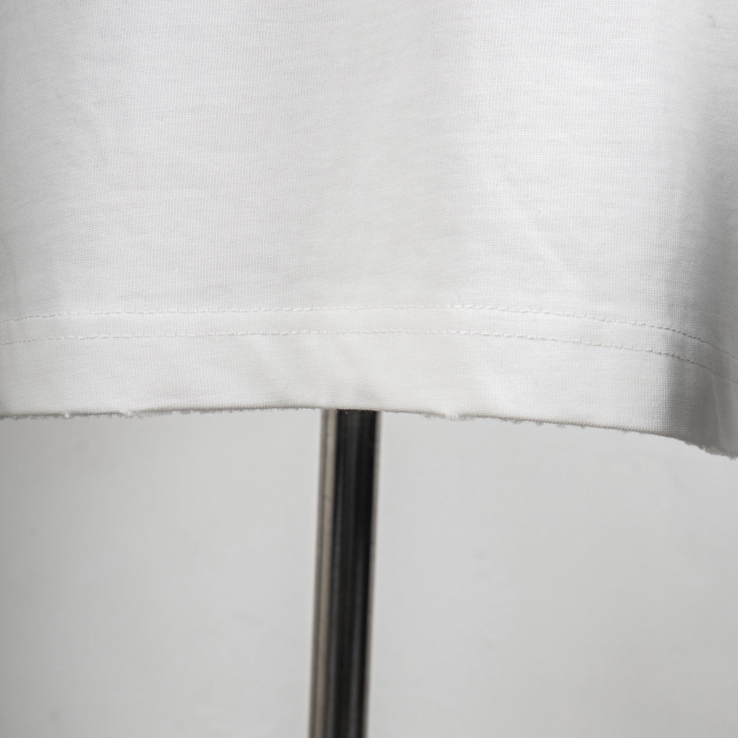 White T-shirt hem with visible stitched edge and seam detail
