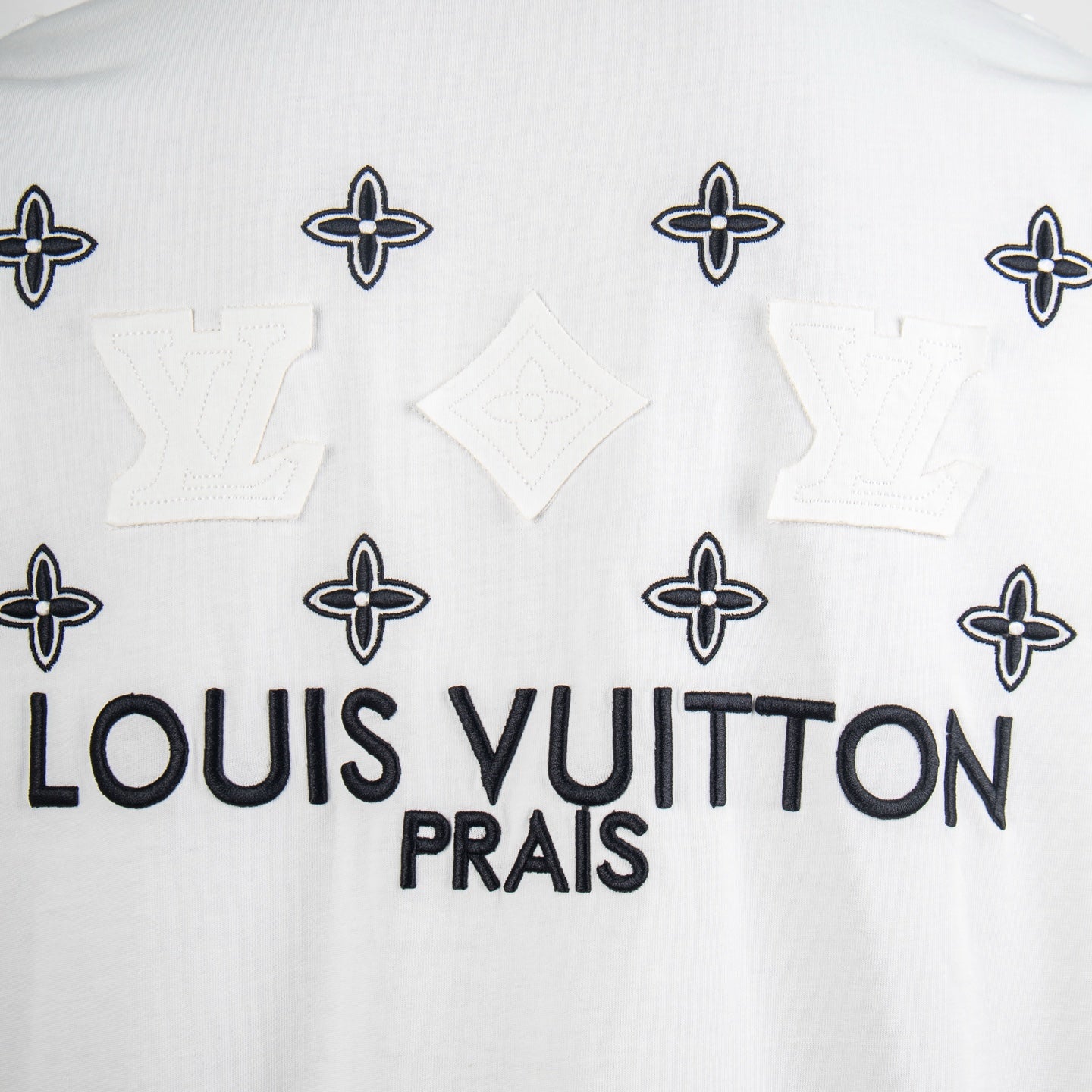 White T-shirt front with Louis Vuitton PRAIS text and navy monogram flower motifs