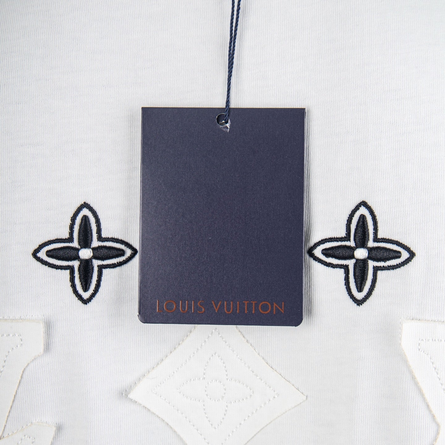 White T-shirt neckline with attached navy tag and fleur-de-lis embroidery